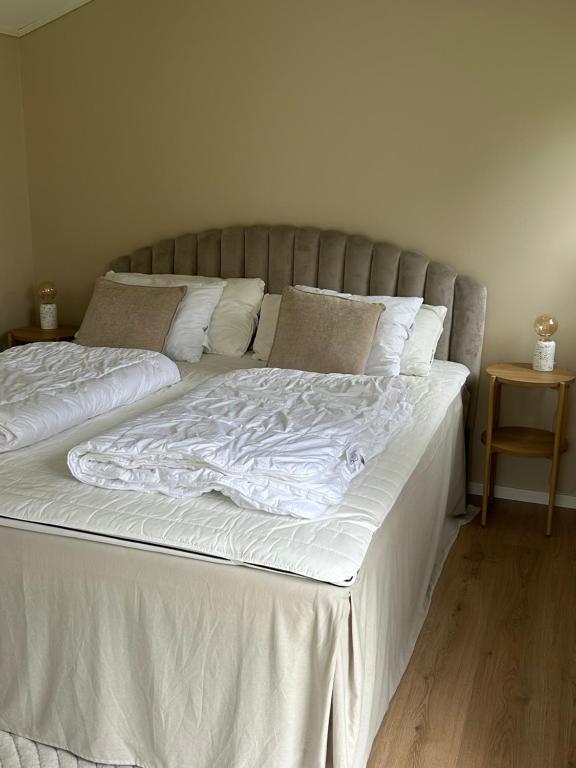 a large bed with white sheets and pillows at Mysigt hus nära hav och skog på härliga Alnö in Alnön
