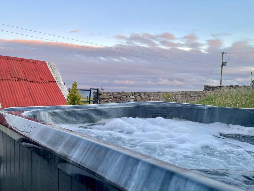 ein mit Wasser gefüllter Whirlpool neben einem Gebäude in der Unterkunft Ceol-na-Mara in Berriedale
