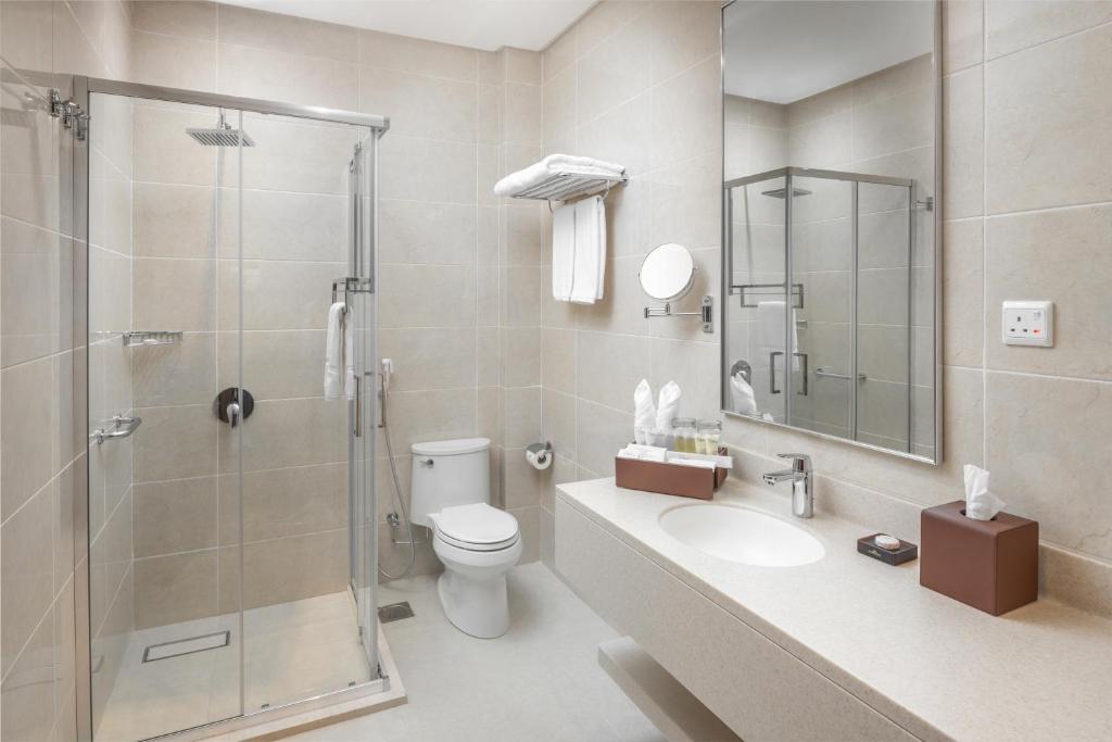 a bathroom with a shower and a toilet and a sink at Landmark Hotels & Suites - Formerly Qamar Hotel in Jeddah
