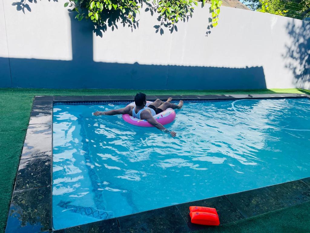 a man laying on a raft in a swimming pool at ANNIKA B&B Claremont in Cape Town