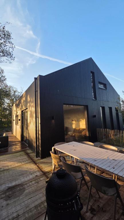 een tafel en stoelen voor een zwart gebouw bij Design Lodge It Sluske Luxe Relax aan Water en Weilanden in Rauwerd