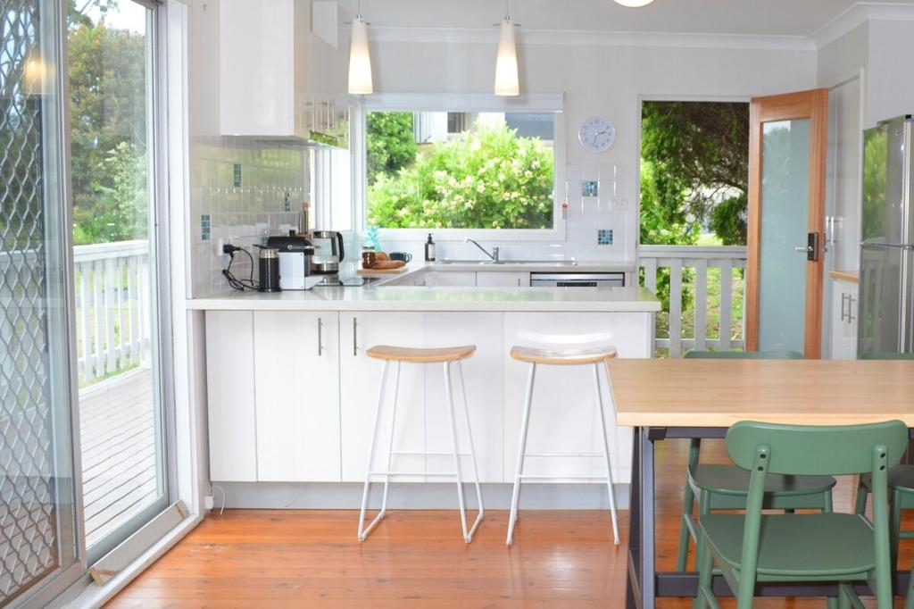 eine Küche mit einem Holztisch und Stühlen in der Unterkunft Classic Meets Contemporary 1960's Beach House in Malua Bay