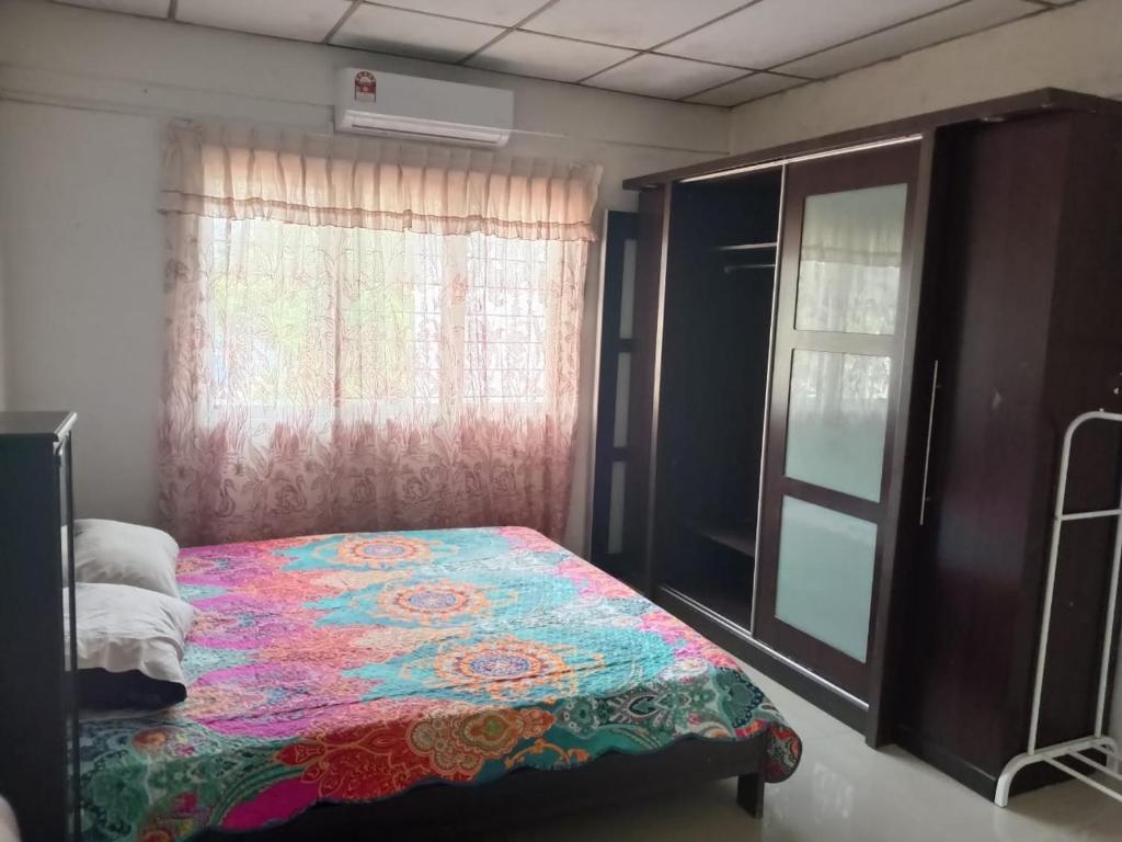 a bedroom with a colorful bed and a window at Asyun Homestay 1 in Sungai Buluh