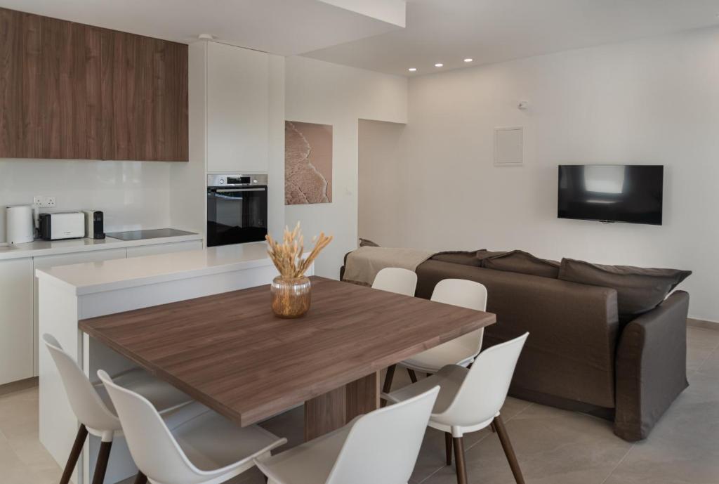 a kitchen and living room with a wooden table and white chairs at Avyra Residences Chrysakama Sea View in Polis Chrysochous