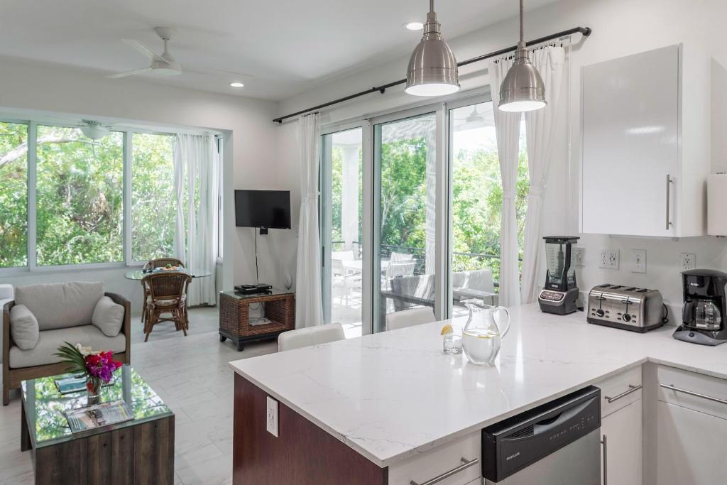 a kitchen and living room with white counter tops and windows at Wyakha 1 Garden View in Long Bay Hills