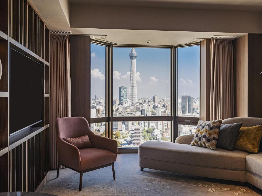 a living room with a couch and a chair and a large window at Asakusa View Hotel in Tokyo