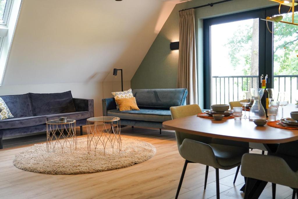 una sala de estar con una mesa y un sofá en Landgoed Erve Triesthaar, en De Lutte