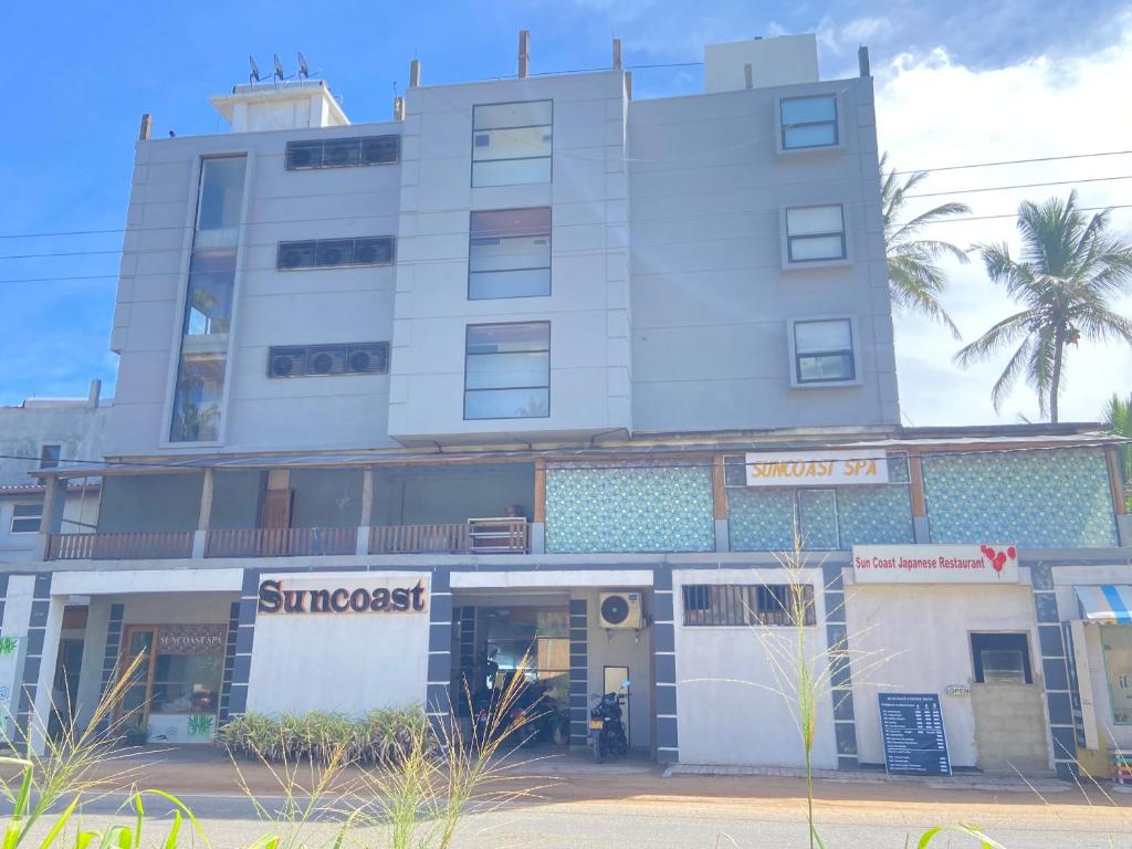 a tall white building with a supermarket in front of it at Suncoast Beach Hotel in Mirissa