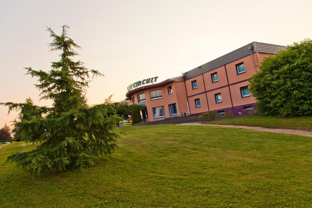 a pine tree in front of a building at Cit'Hotel Du Circuit in Magny-Cours