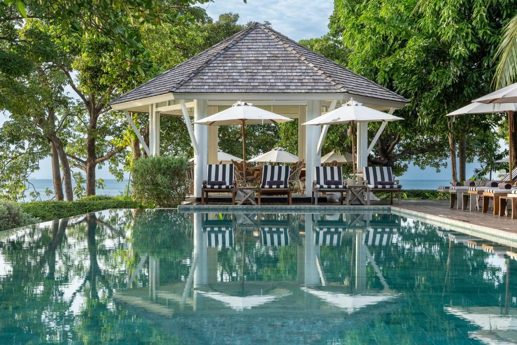 ein Pool in einem Resort mit Stühlen und Sonnenschirmen in der Unterkunft Cape Kudu Hotel, Koh Yao Noi in Ko Yao Noi