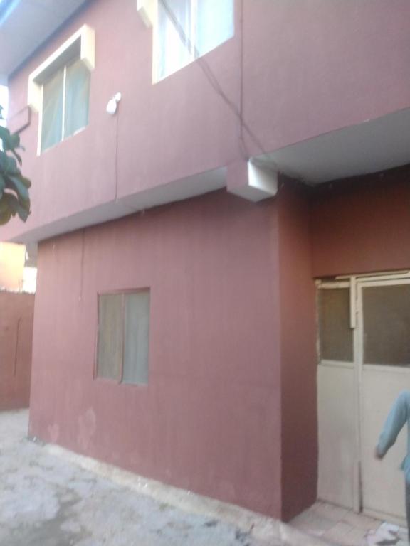a pink building with a door on the side at Ensuite in Ejigbo