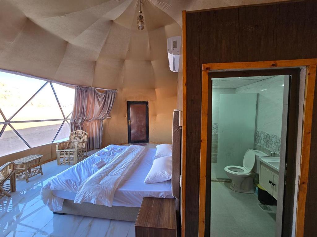 a bedroom with a large bed and a bathroom at Talira Luxury Camp in Wadi Rum