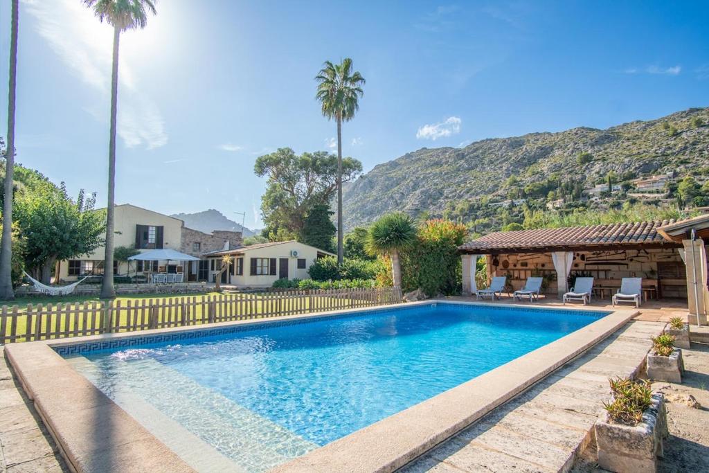 a swimming pool with palm trees and a house at Can Gat in Pollença