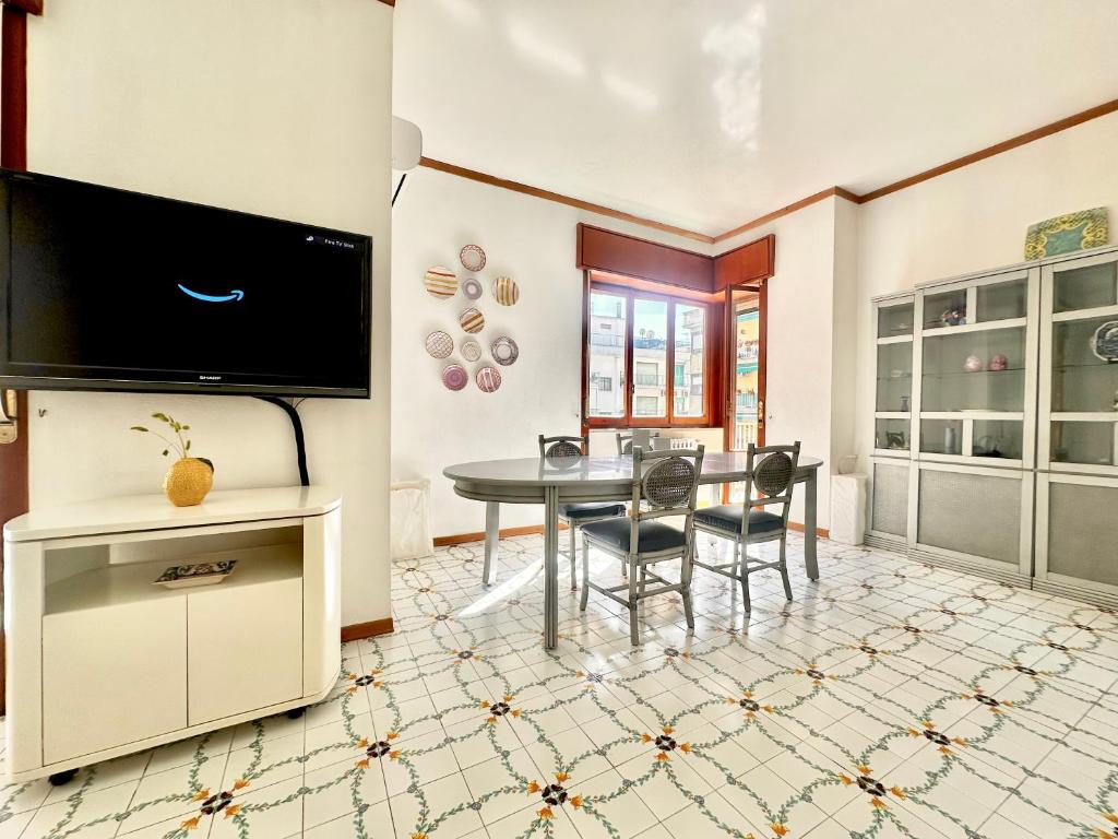 a dining room with a table and a tv at Large family appartament with pool in Sorrento