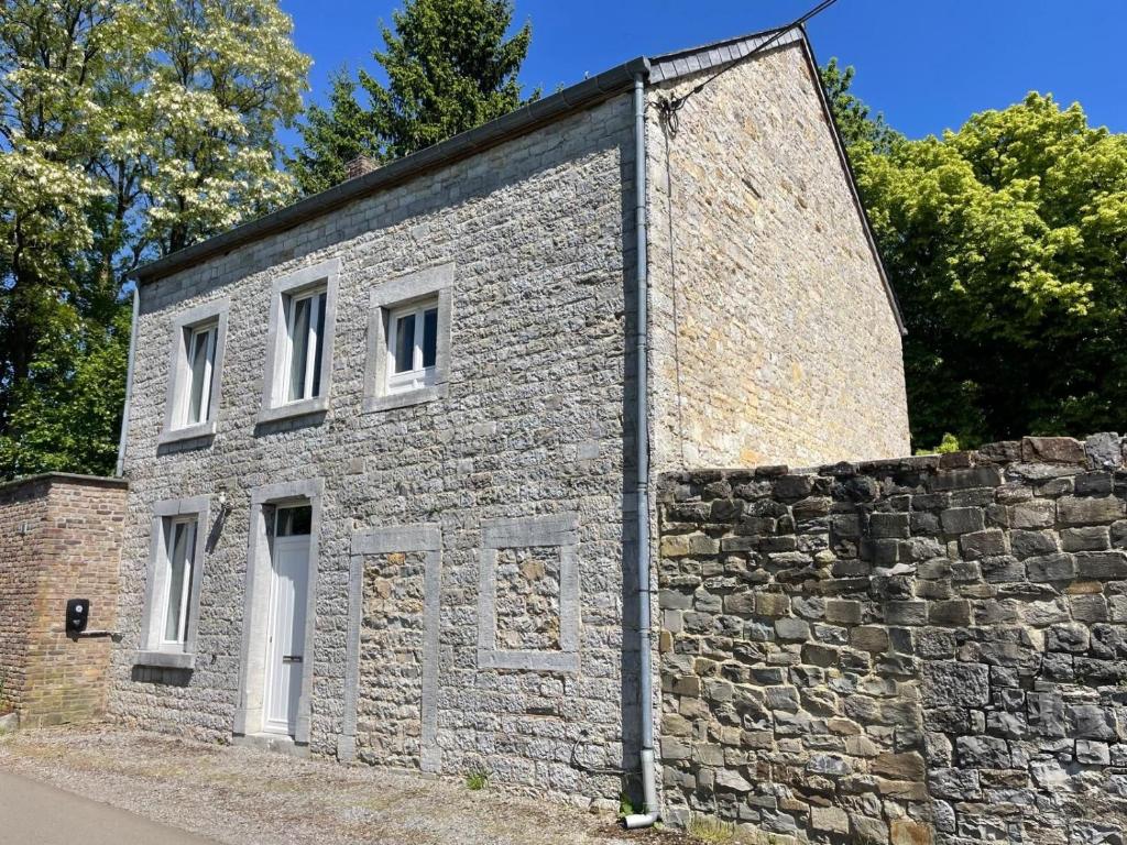 a brick building with white windows and a stone wall at Au petit Clocher - vakantiehuis Ardennen in Ferrières