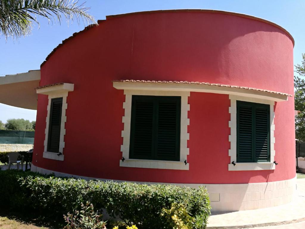 Casa roja con ventanas con contraventanas verdes en Villa Costanzo al mare, en Avola