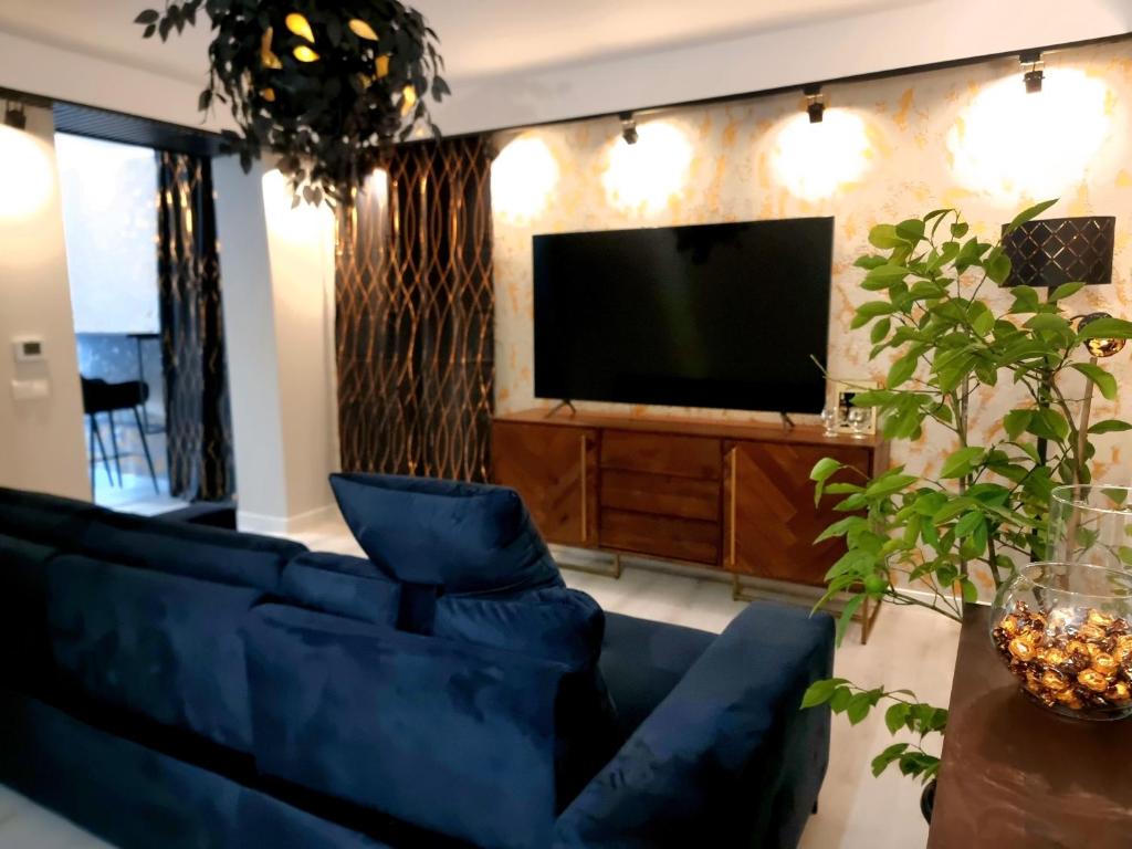 a living room with a blue couch and a television at GLAMOUR VOX Jacuzzi & Club in Cluj-Napoca