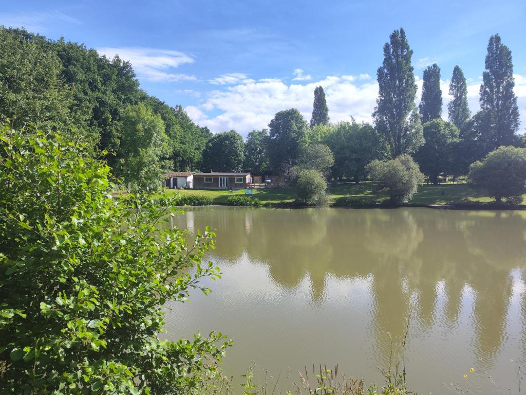 a view of a lake with a house in the background at Astral in Prunay-Cassereau