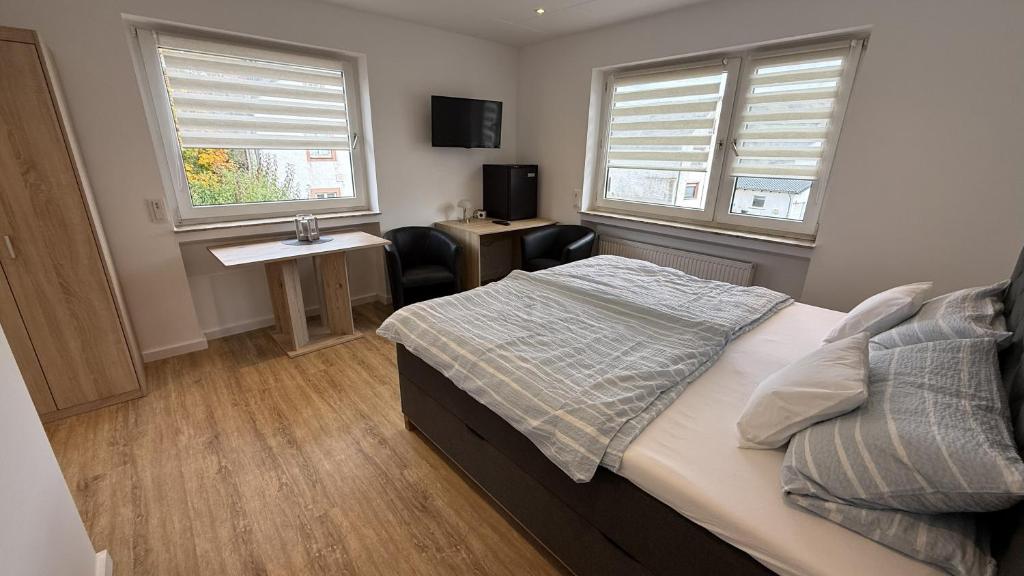 Un dormitorio con una cama y un escritorio y dos ventanas. en Gästehaus Fries, en Blankenheim