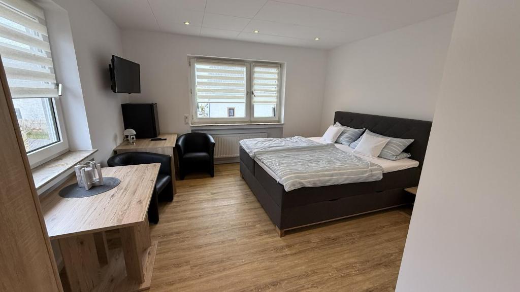 a bedroom with a bed and a table and a desk at Gästehaus Fries in Blankenheim