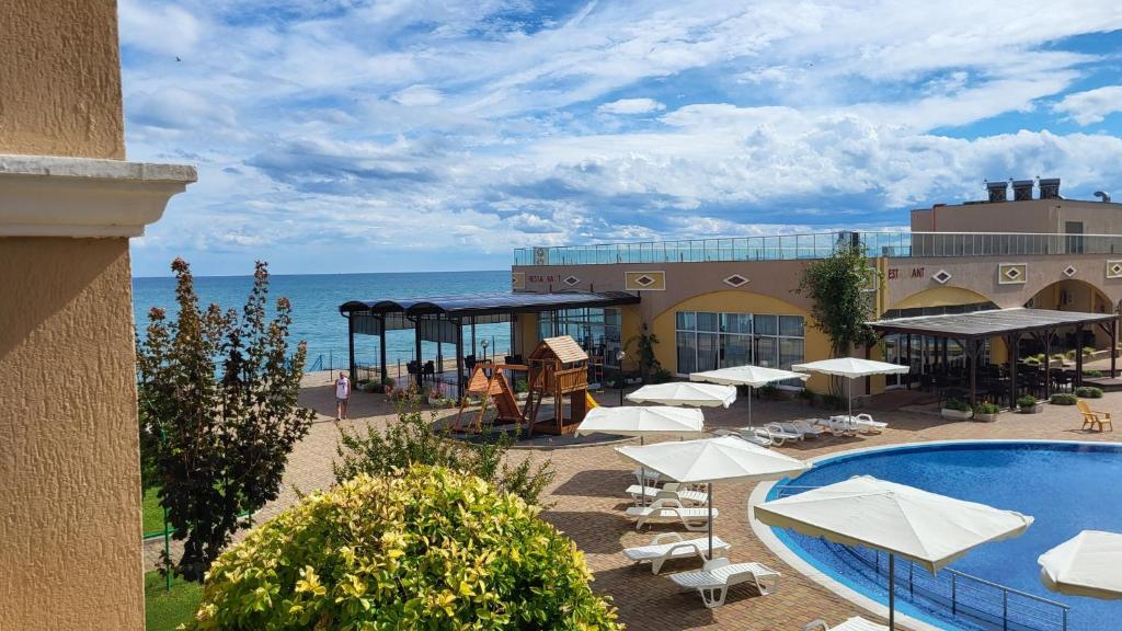 a resort with a pool and tables and umbrellas at Studio F210 - Bulharsko in Aheloy