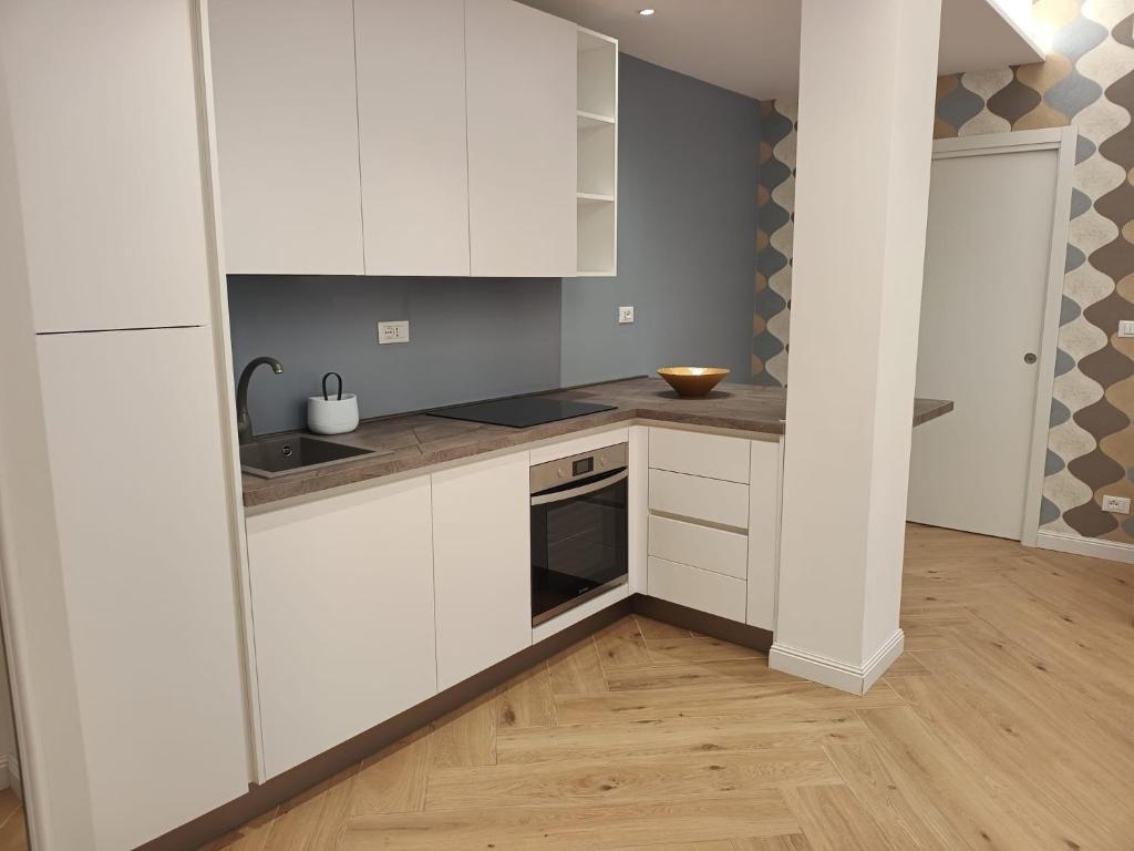 a kitchen with white cabinets and a wooden floor at Appartamento in centro in Termoli