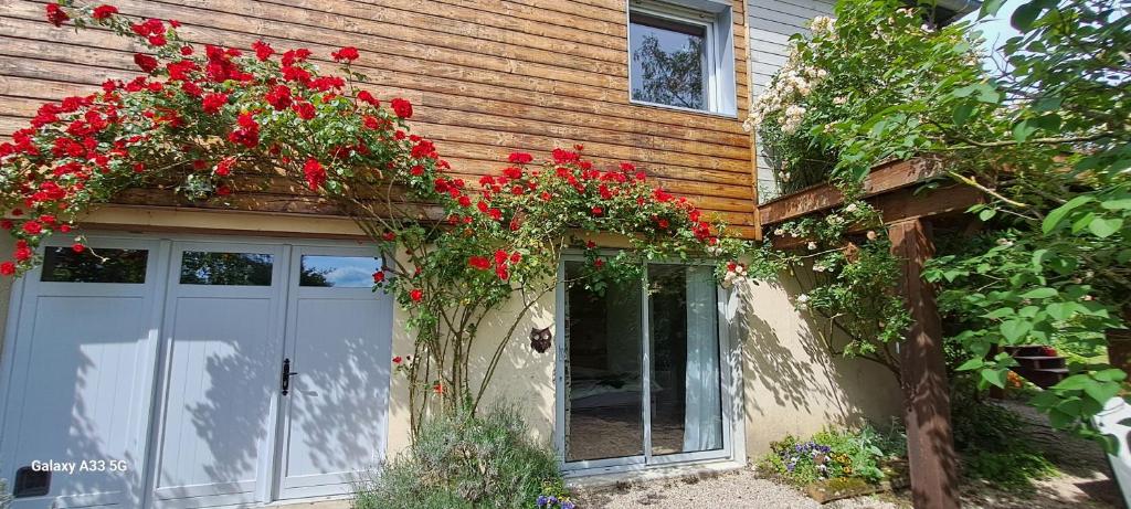 une maison avec des fleurs rouges devant une porte dans l'établissement Studio Nature, à Marboz