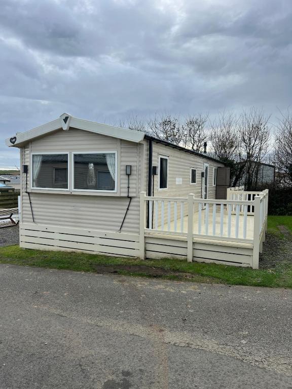 una pequeña casa con una cerca blanca al lado en Beautiful Holiday Home Close to the Sea, en Poughill