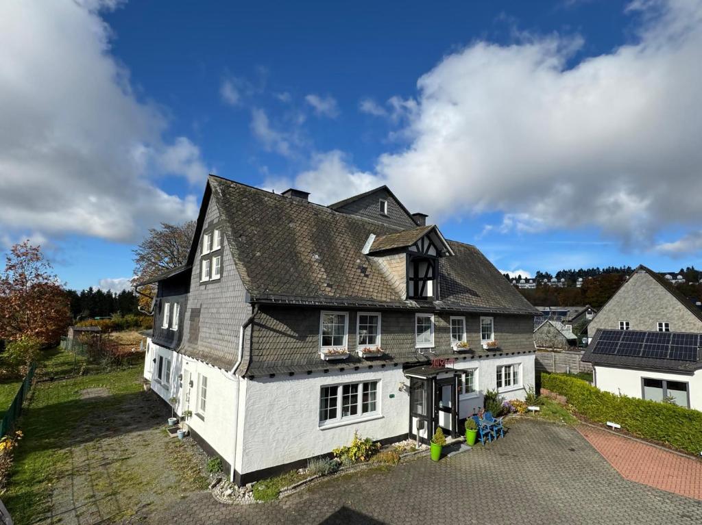 a large white house with a black roof at Pension Haus All Seasons in Winterberg
