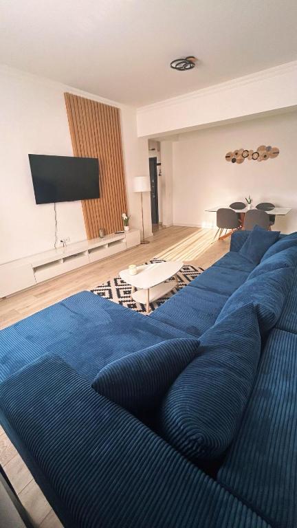 a living room with a blue couch and a flat screen tv at Mareea Luxury Apartment-Energia Residence in Constanţa