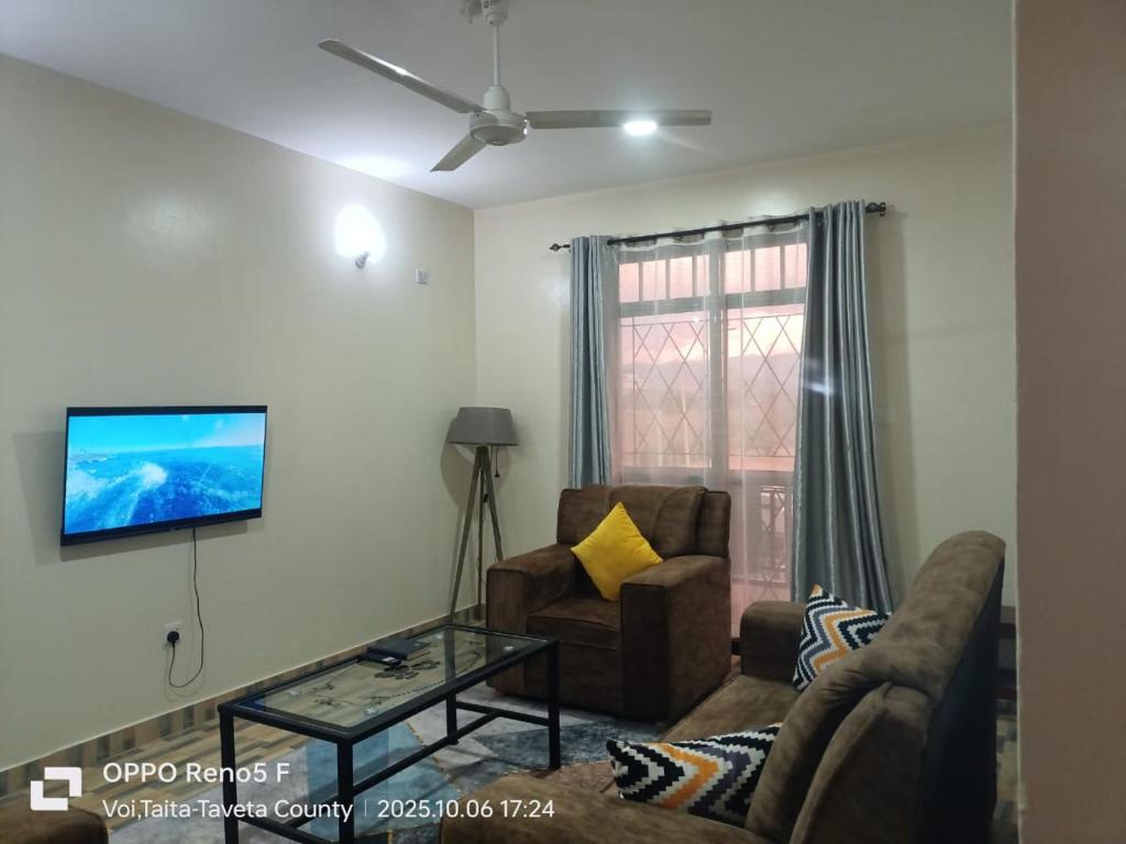 a living room with a couch and a tv on the wall at 1 Bedroom Fully Furnished Luxurious Apartment Voi Town in Voi