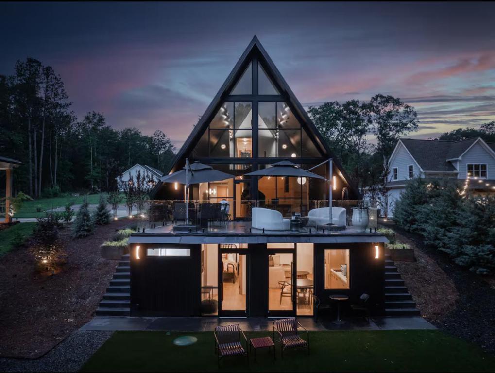 ein großes Haus mit einem dreieckigen Dach mit Lichtern in der Unterkunft Midnight Raven Lake House - luxury a-frame w boat in Reed Creek