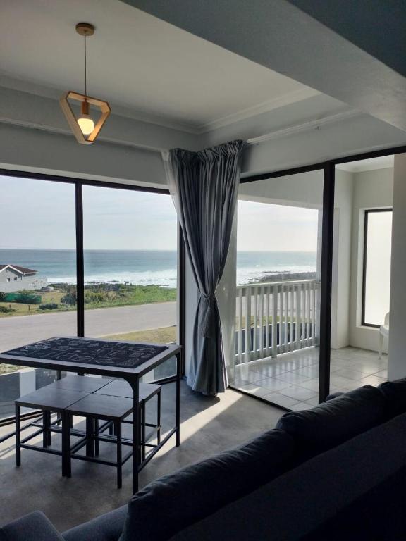 a living room with a table and a view of the ocean at Driftwoods in Gqeberha