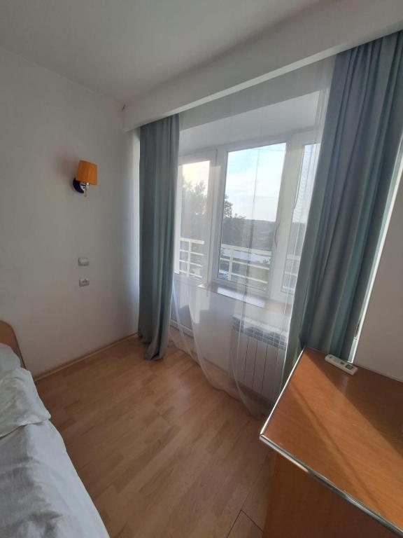a bedroom with a bed and a large window at Qorjyn Hotel in Shymkent