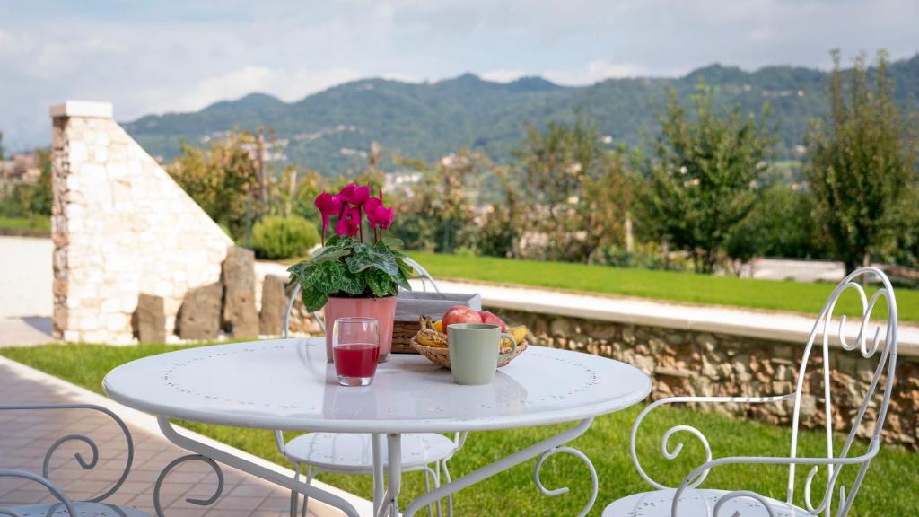 a white table with a vase of flowers and a basket of fruit at Sassimori casa vacanza in Chiampo