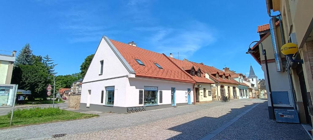a white building with a red roof on a street at Apartmán Jana in Vysoké Mýto