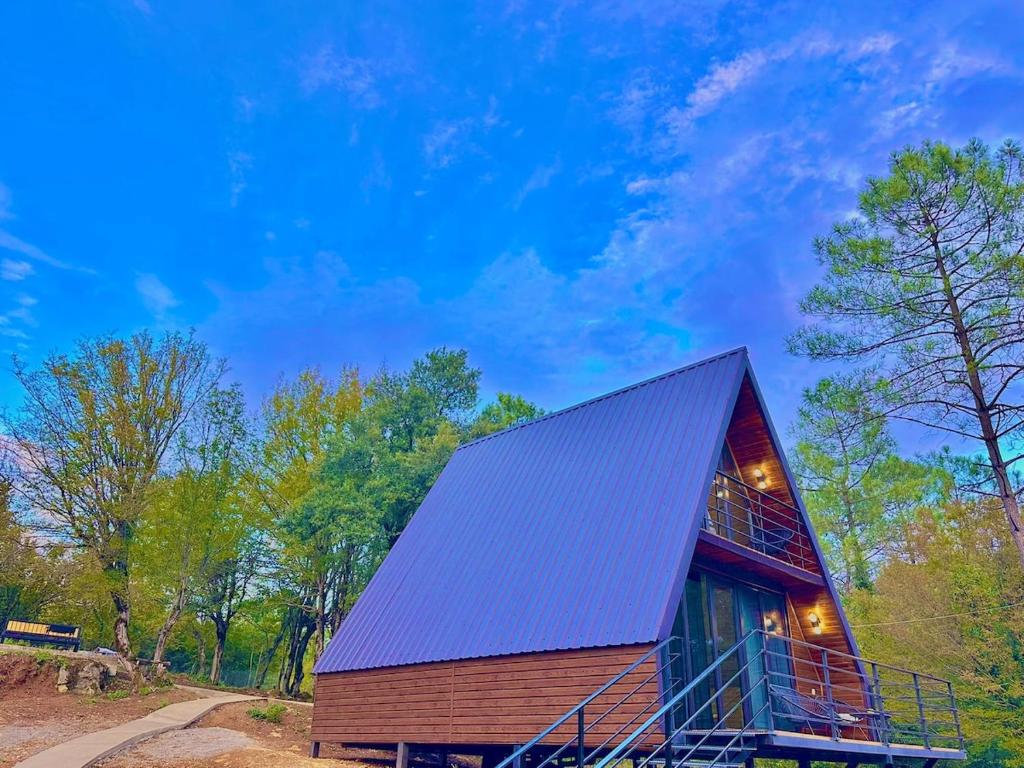 eine Hütte im Wald mit einem Metalldach in der Unterkunft Cozy wooden cottage in the forest 2 km from Kutais in Kutaissi