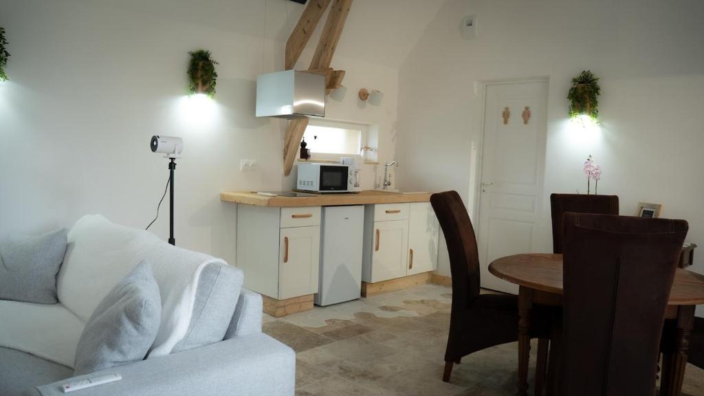 a living room with a couch and a kitchen at Le Refuge Des Saisons 