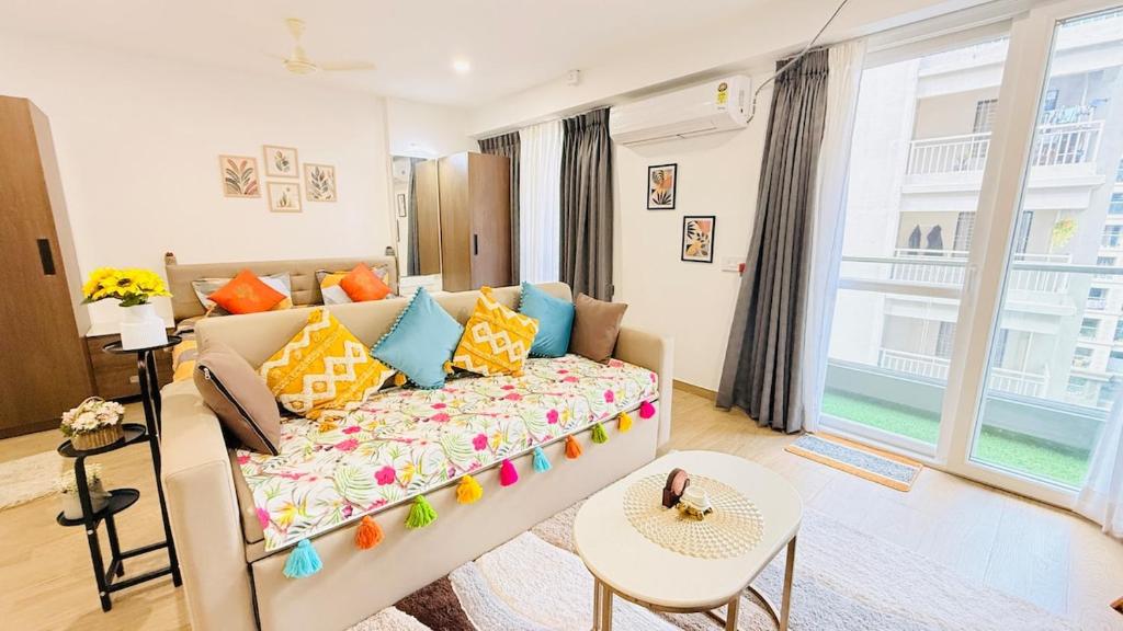 een woonkamer met een bank en een groot raam bij Airport Oasis Near Pune Airport Symbiosis College in Pune