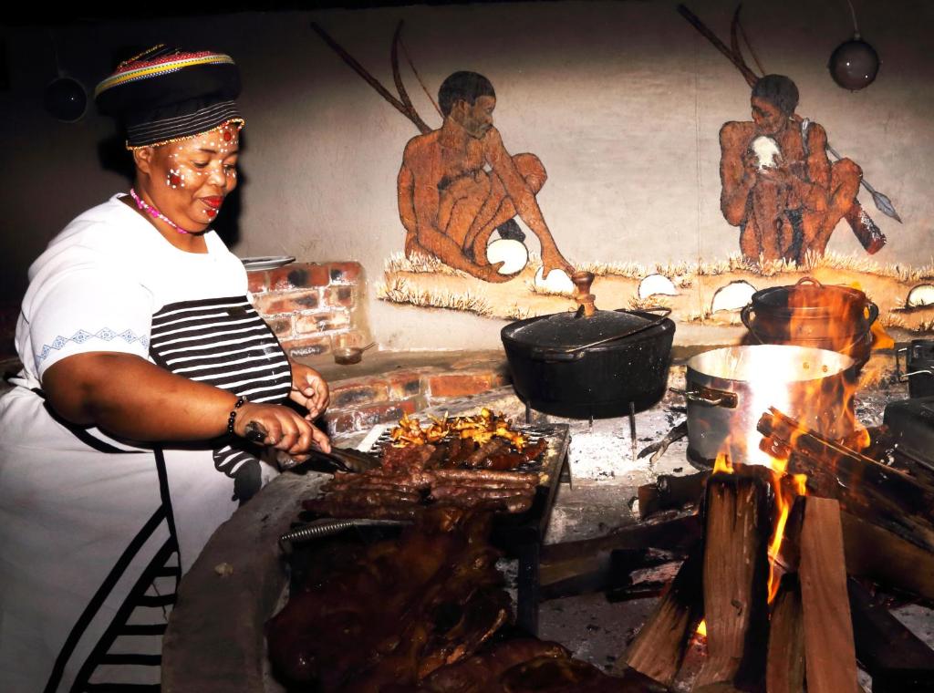 a woman is cooking food on a grill at The Backpack Shack in Mossel Bay