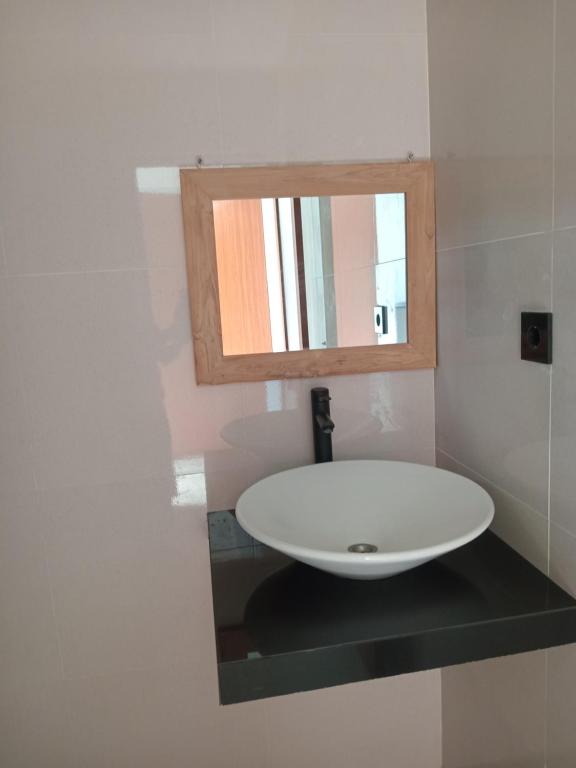 une salle de bain avec un lavabo blanc et un miroir dans l'établissement Jagadhita villa, à Ubud