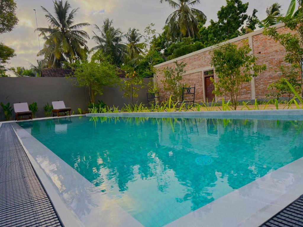 a swimming pool with blue water in front of a building at Dhyana Beach Villa in Ambalangoda