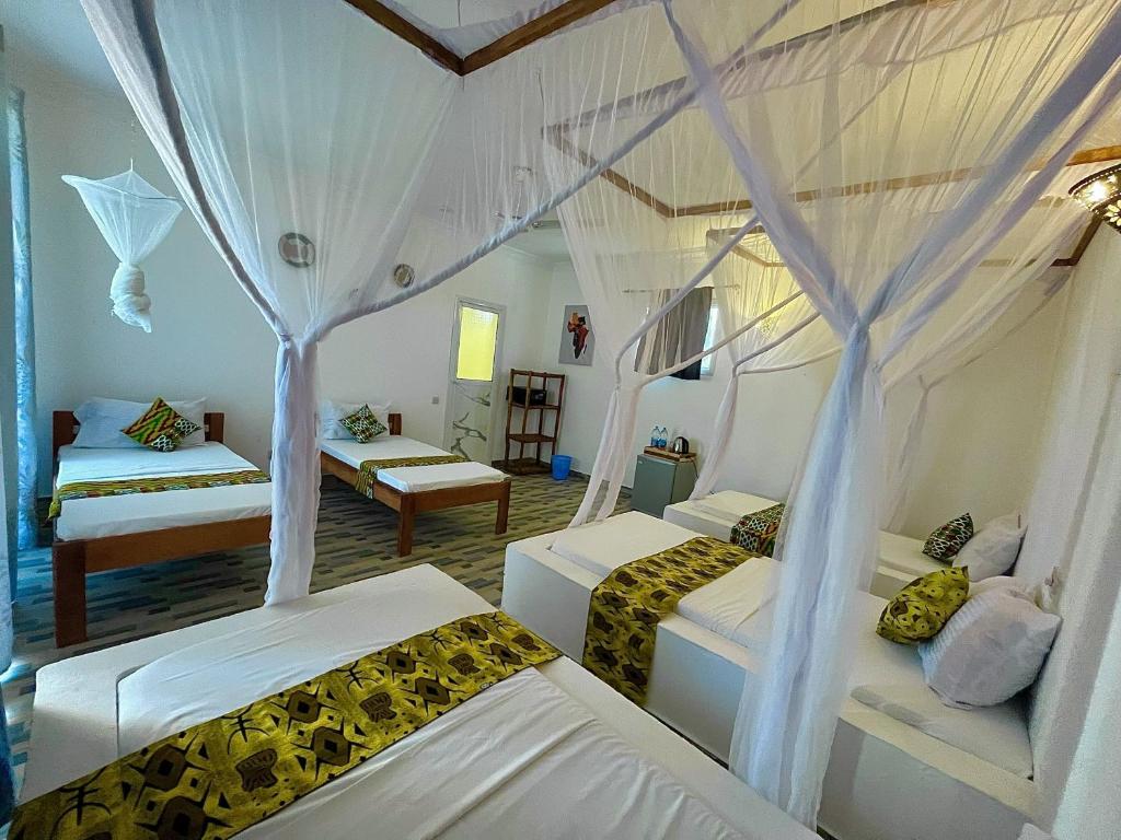 a bedroom with two beds and a room with two beds at Karibu House Paje in Paje
