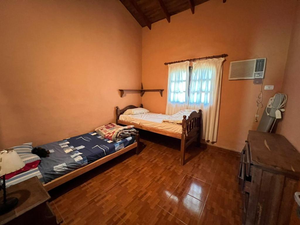 a room with two beds and a window in it at Lujoso Chalé frente al Río con Piscina in Paso de la Patria