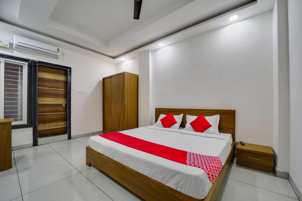a bedroom with a large bed with red pillows at Hotel O Swastik in Bhopal