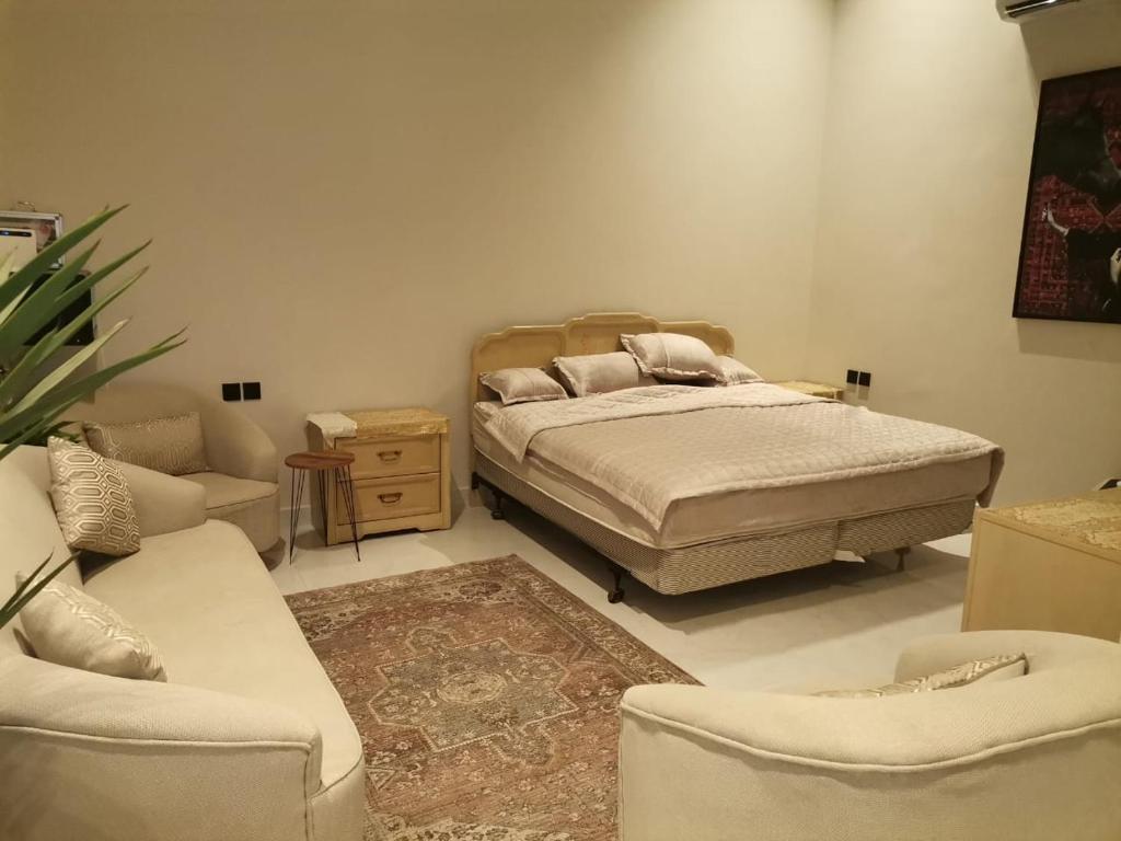a bedroom with a bed and a couch and chairs at شاليه ياسمين الشروق الأولى للمناسبات in Quai