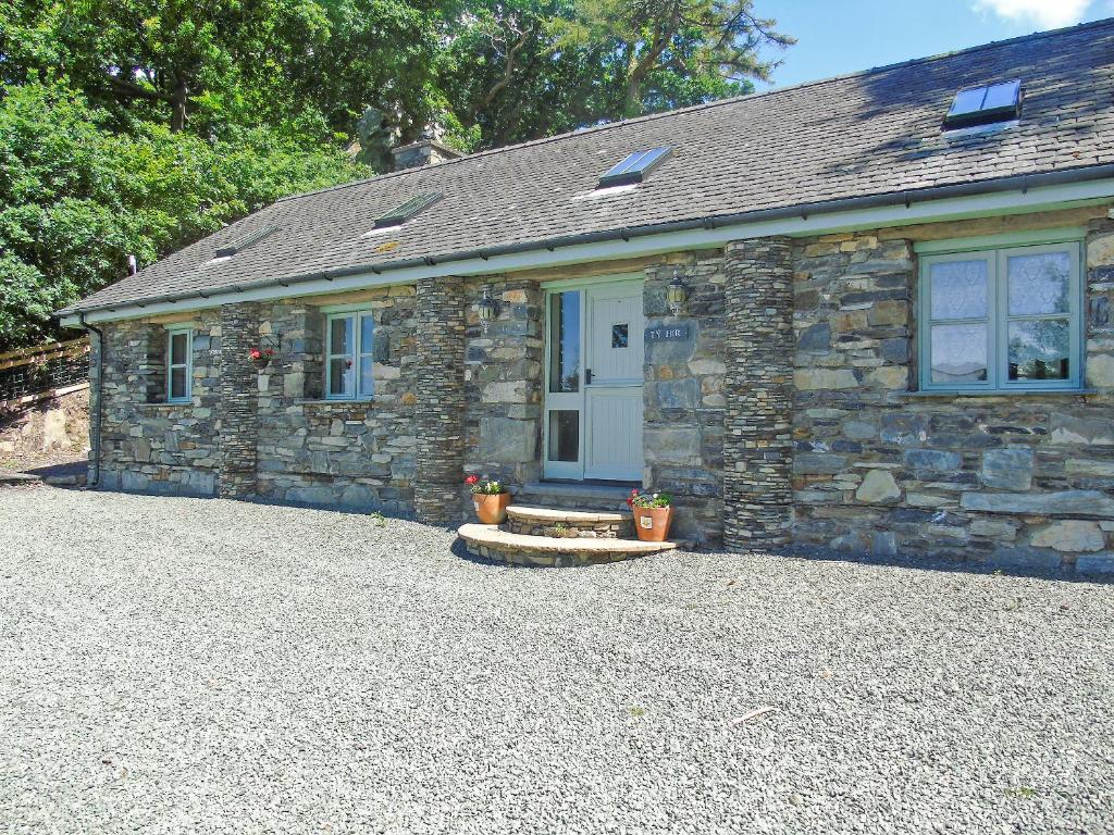 a stone cottage with a door on a gravel driveway at Ty Hir Bwlch Gwyn Farm Equestrian Centre in Fairbourne