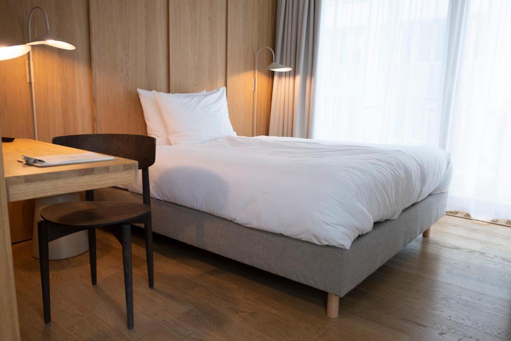 a hotel room with a bed and a desk and a bed and a table at Das Kaya Hotel Stuttgart Airport Messe in Filderstadt