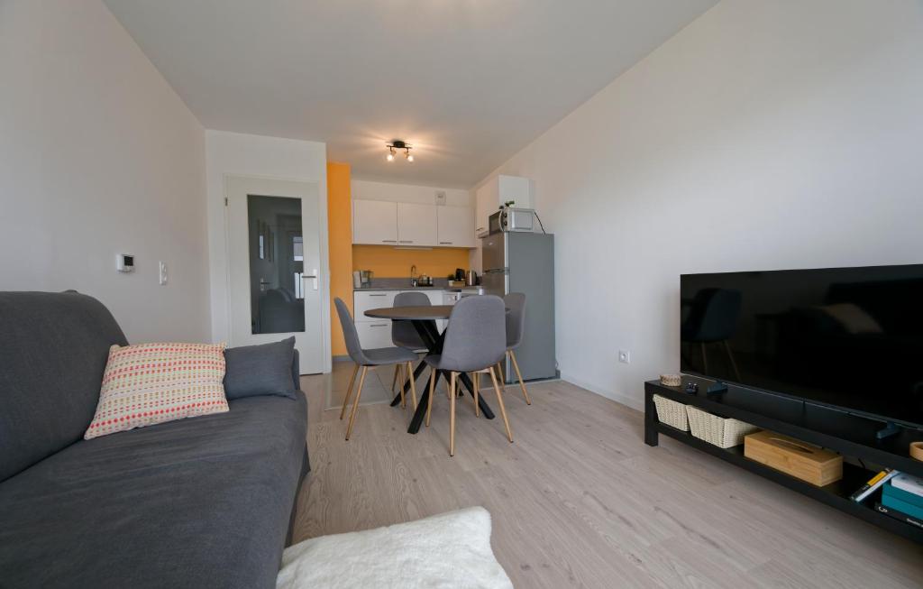 a living room with a couch and a table with chairs at Sarananda - apartment in Saint-Valery-sur-Somme