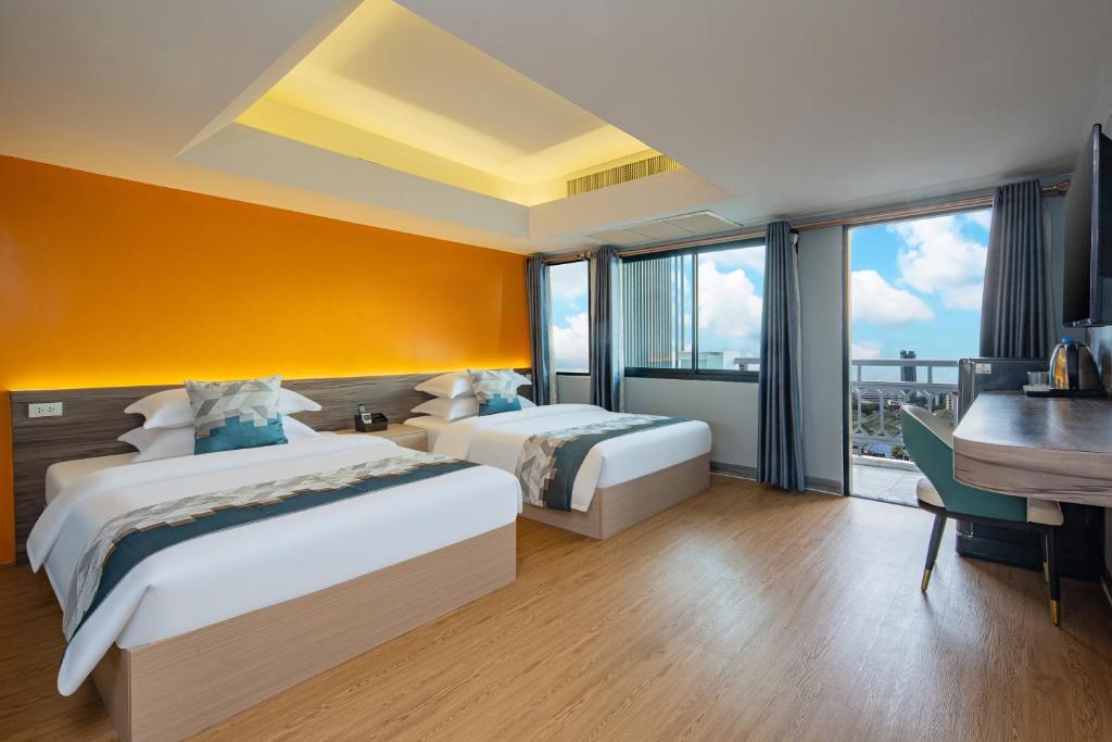 a hotel room with two beds and a desk and a table at Xinmylin Boutique Resort Hotel in North Pattaya
